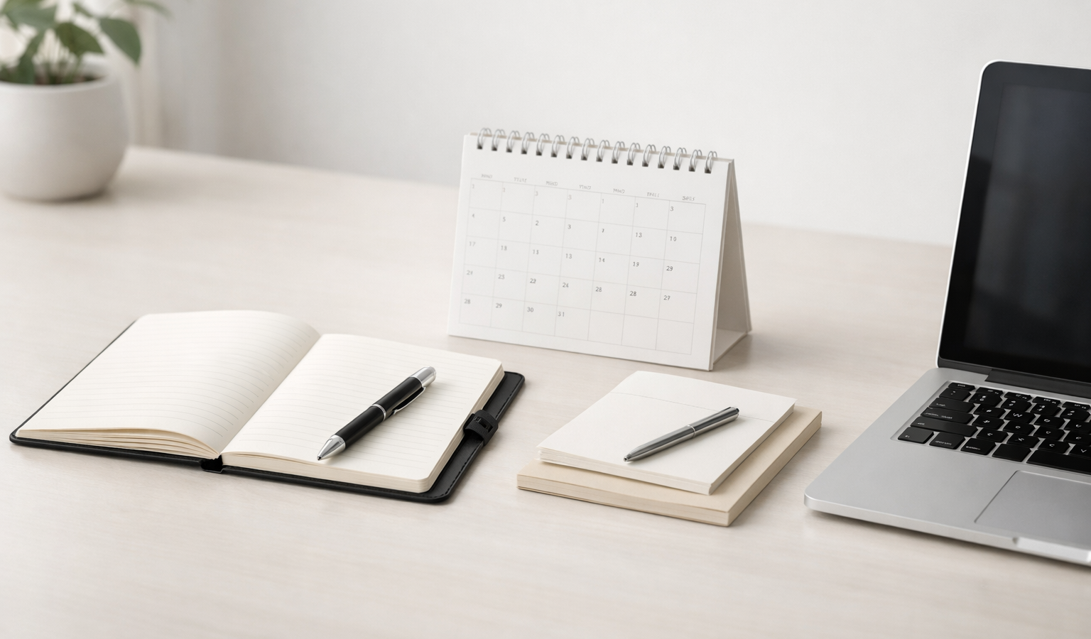 Minimal modern desk setup with a notebook, calendar, and laptop for a weekly review article.